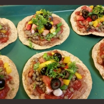 A tostada topped with refried beans, salsa, lentils, tomatoes, yellow peppers, olives, green onions, and cilantro. Baked in 250 degree oven for about 10 minutes.