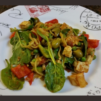 Tofu and pasta dish with spinach, red and green peppers, green olives, pineapple, and peas.